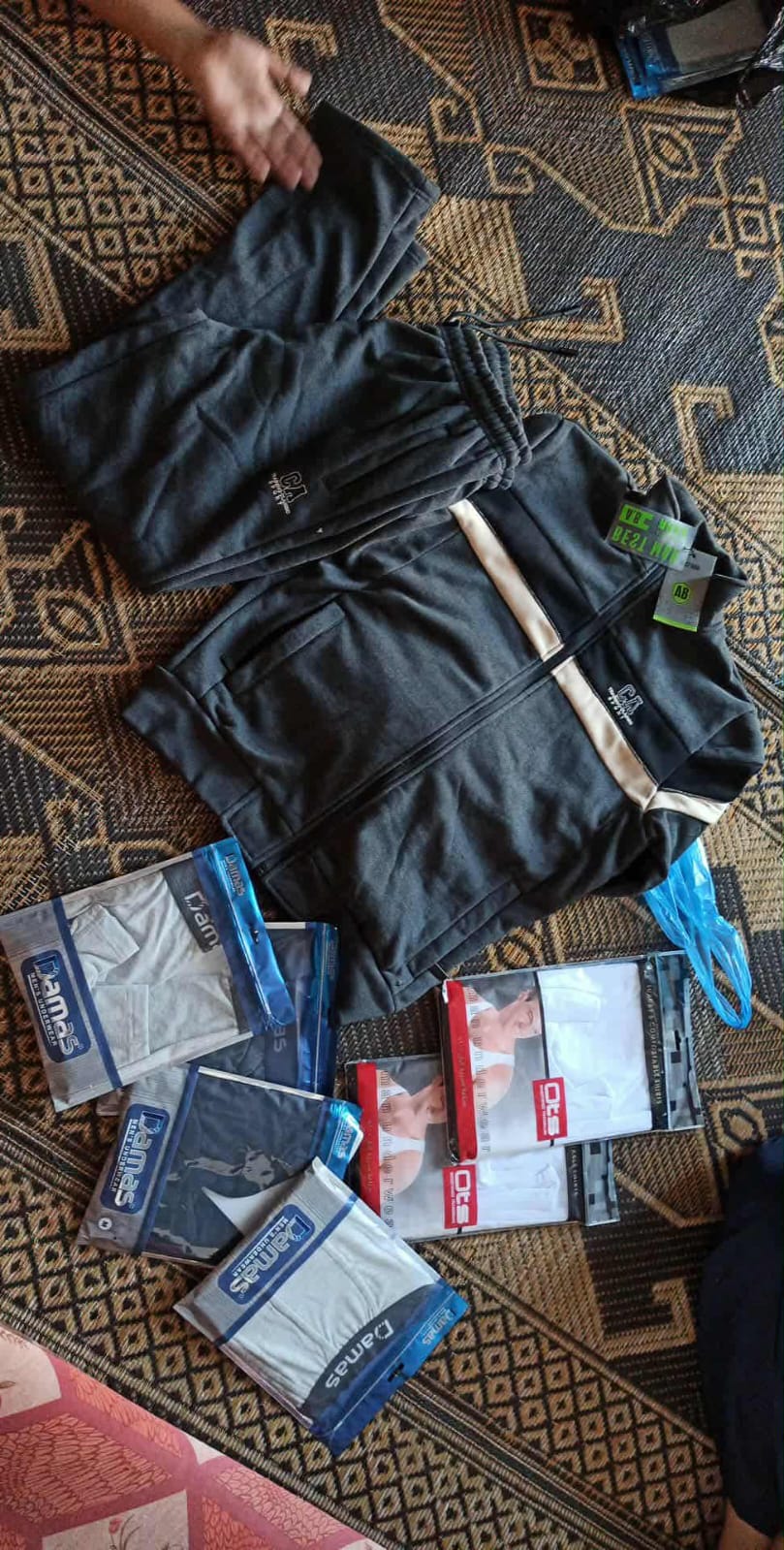 A tracksuit and packaged clothing laid out on a patterned mat