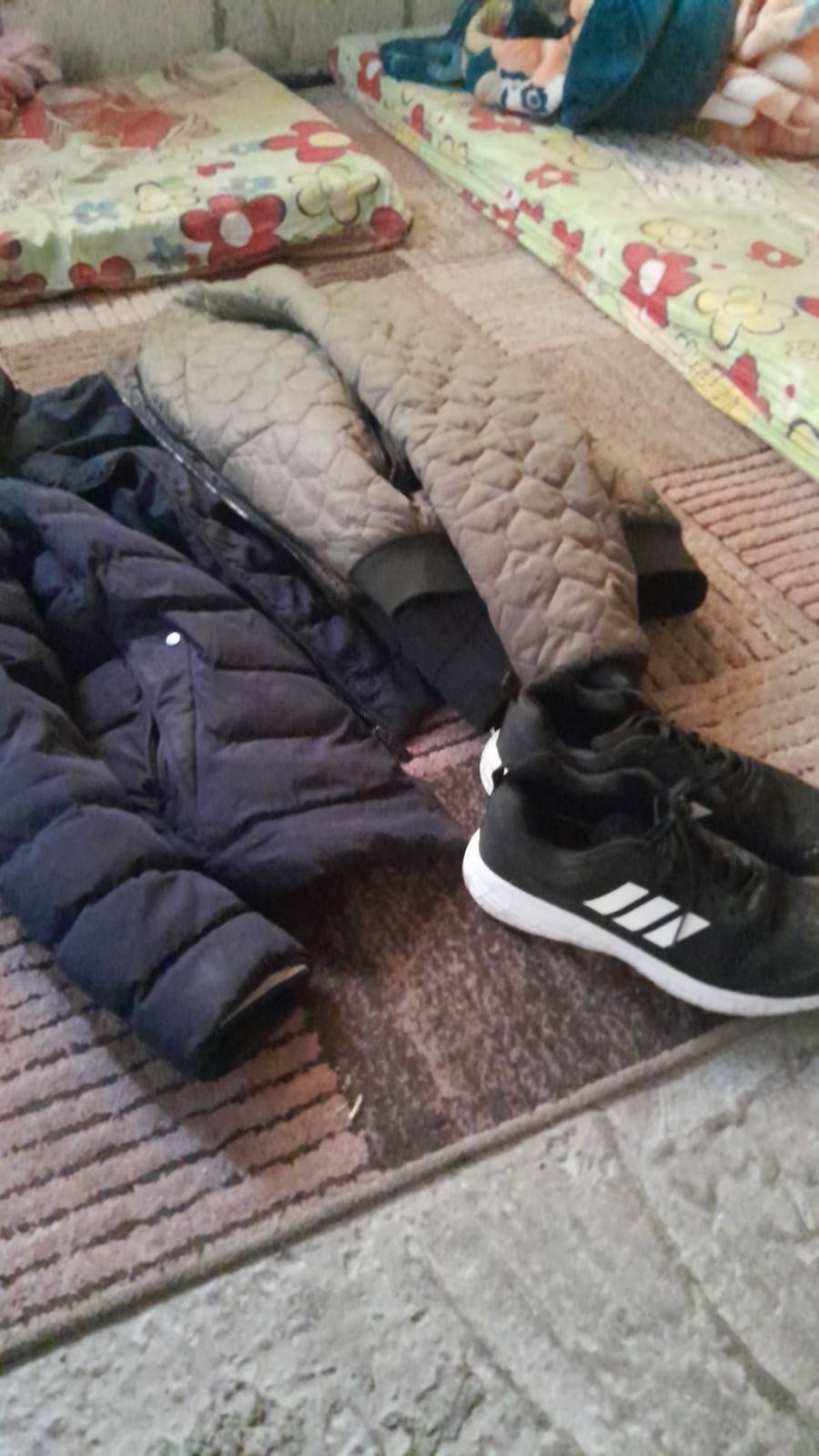Winter coats and shoes laid out beside foam mattresses